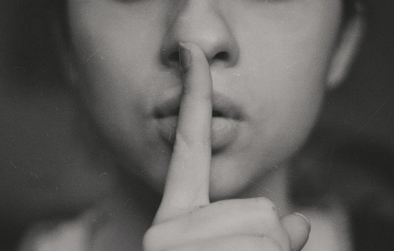Ladies face with finsh raised to lips as in shush