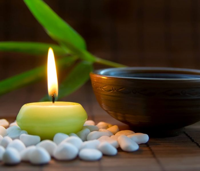 A small light candle surrouned by white pebbles